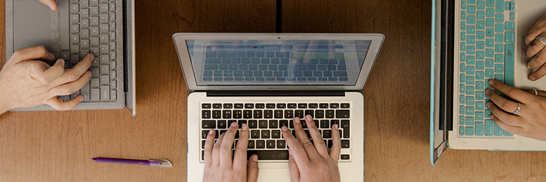 three laptops with hands typing on them