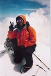 Man on top of mountain in climbing gear.