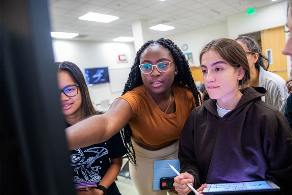 Students collaborate around computer screen