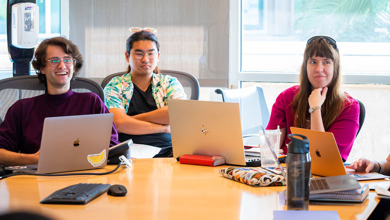 Chapman University students gather around classroom table with laptops and collaborate