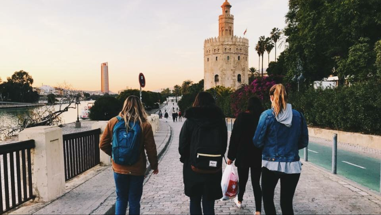 Students walking down cobblestone road next to river in Spain