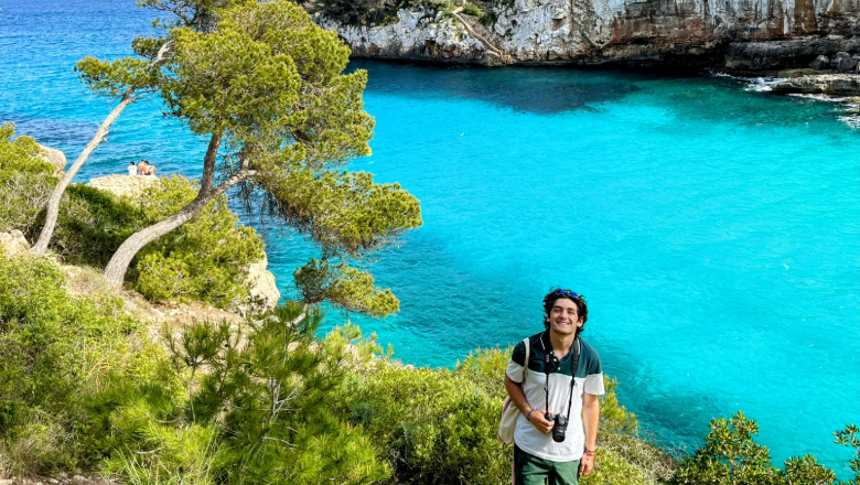 Chapman University student stand on hill in front of bright blue waters while studying abroad