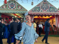 Girls dances in flowy blue dress in front of colorful tents