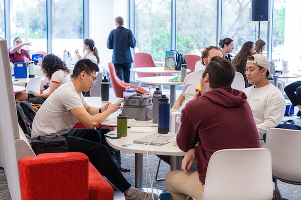 Student sit at tables in a common study area on Rinker Campus.