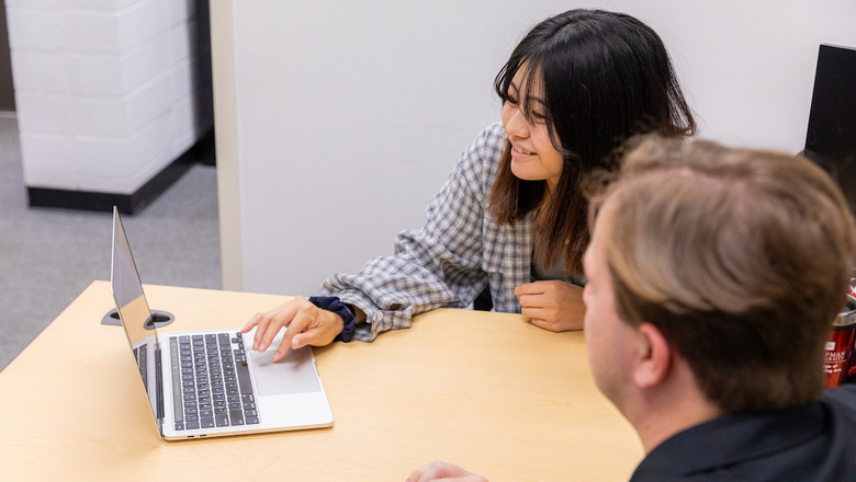 A student and an advisor work on a laptop.