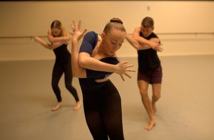 Three students dance in a dance studio.