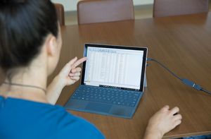 A student poining to a laptop screen displaying rows of data