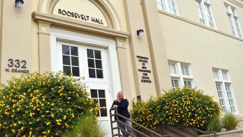 Erin Berthon standing on stain front of Roosevelt Hall