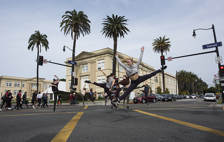 People dancing in the middle of a crosswalk in a  4-way intersection