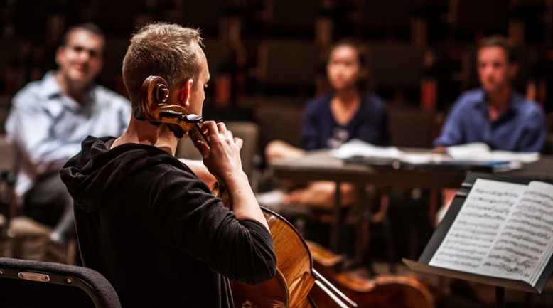 student performing cello for class