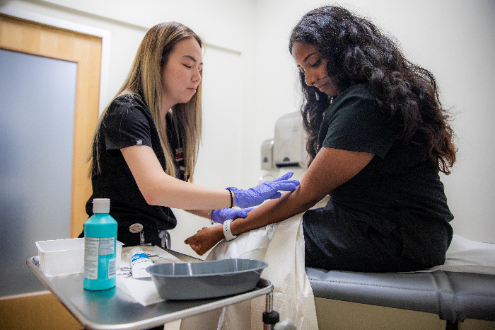 Two medical professionals sterilizing a patients arm