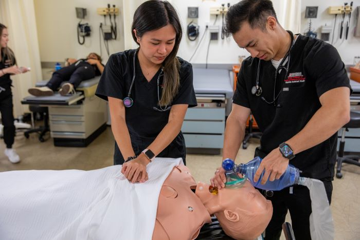 Two medical professional putting a mask on a medical dummy