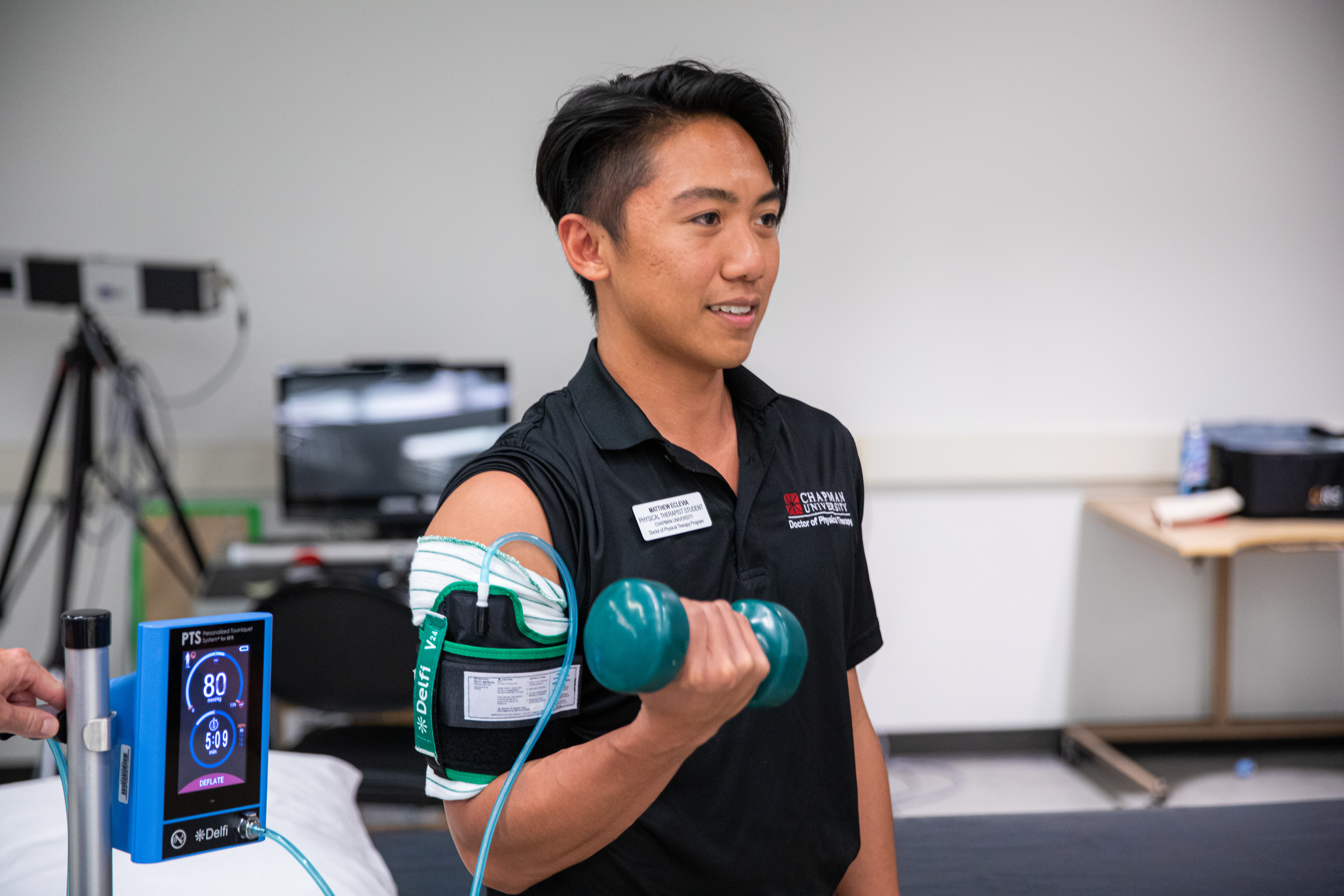 Student lifts dumbbell with monitor hooked up to bicep area