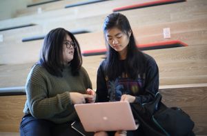 Two screenwriting students sitting on steps and looking at a laptop