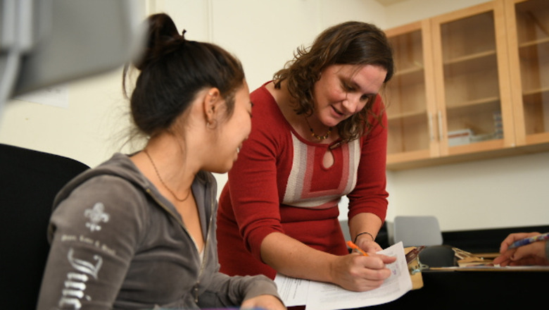 A student and an advisor in a classroom. They are going over some papers.