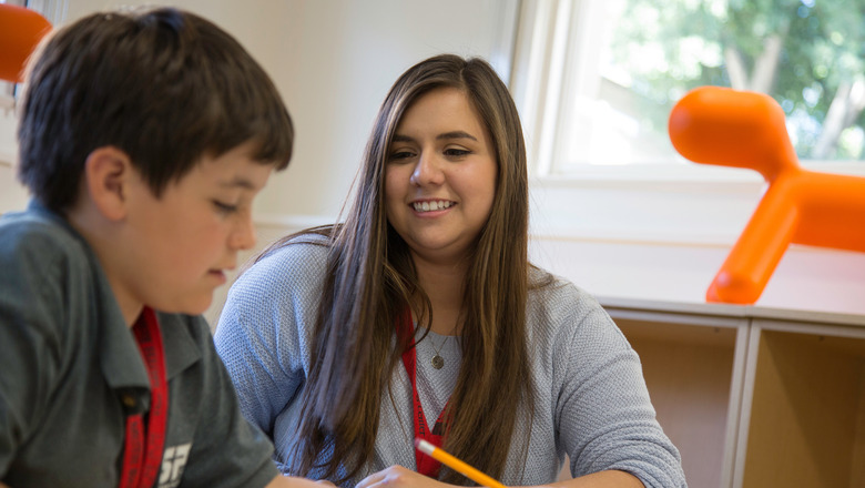 A student teacher and an elementary-aged student in a classroom.