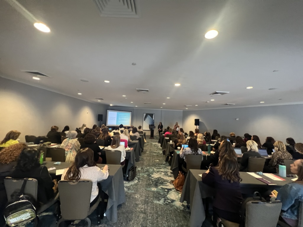 people sitting at tables watching a presentation 