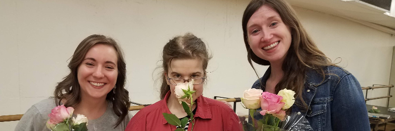 Two FAST interns and a FAST member holding flowers and smiling