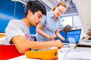 Students working in class, assembling devices.