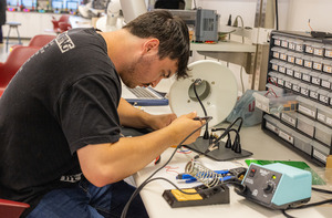 Students working in class, assembling devices.