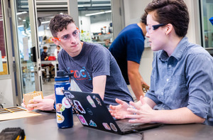 Students work in a lab. There is a laptop and a water bottle on the desk.