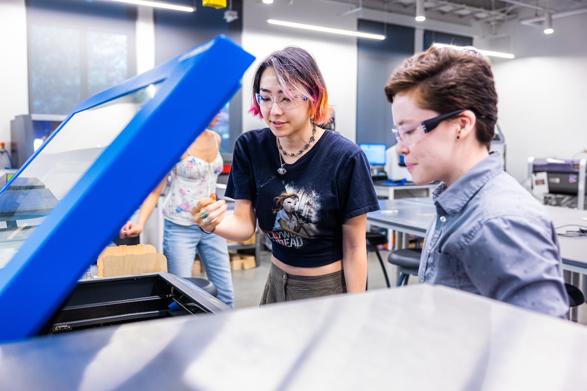 Student and staff looking at equipment in Makerspace