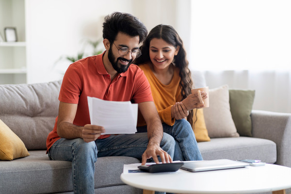 Young couple sitting on couch in front of laptop 