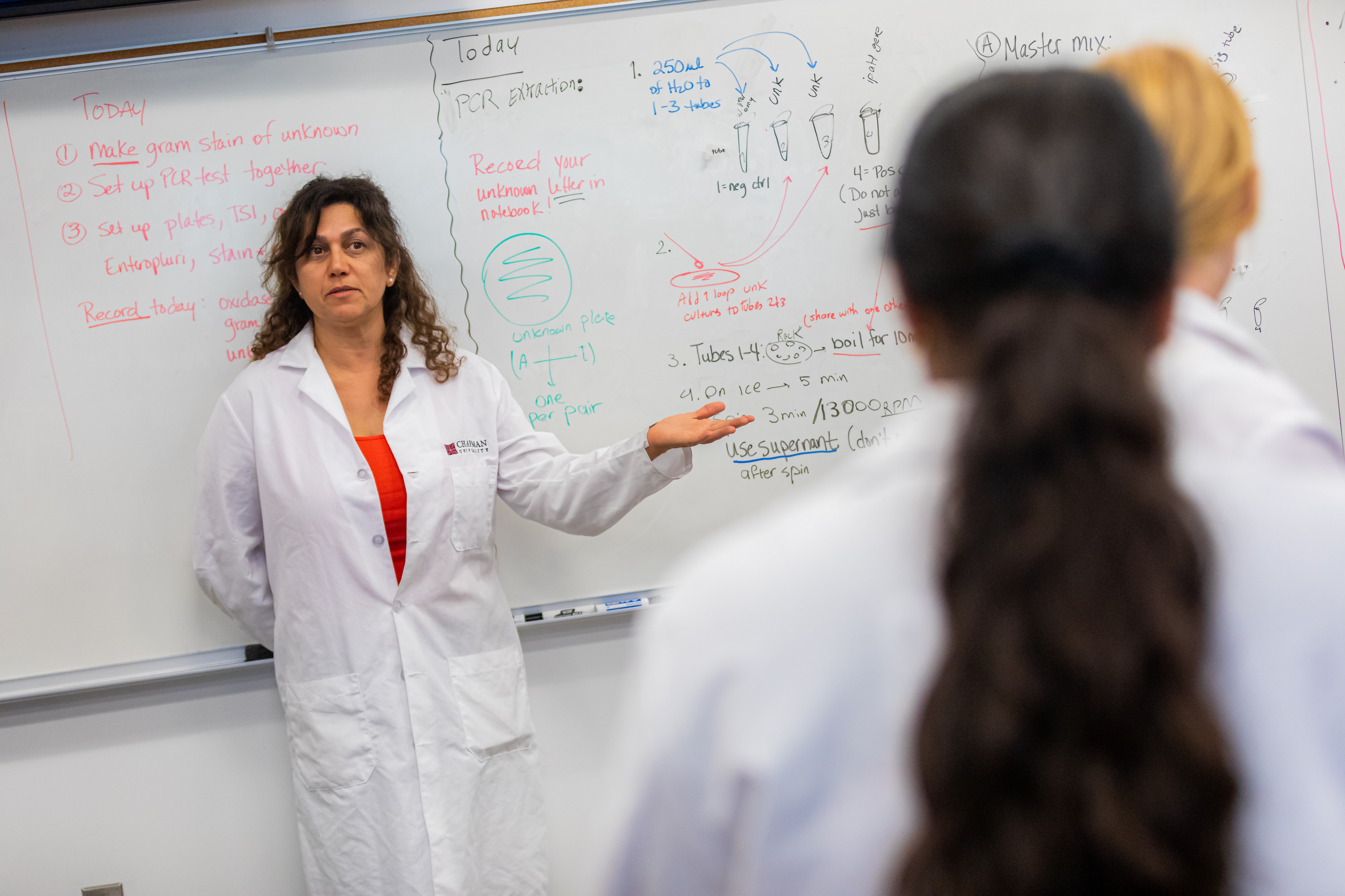 Woman with curly hair in a lab coat lecturing