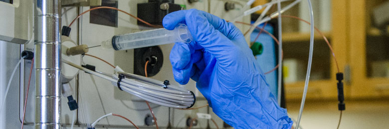 hand with syringe putting into pharmacy equipment