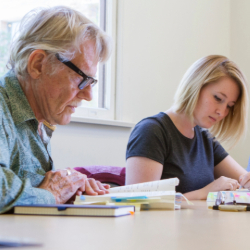 Man and woman read books at a desk