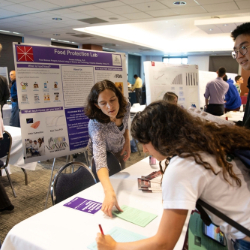 Woman signs paper at booth at expo event