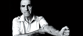 black and white photo of a Holocaust survivor showing his tattoo