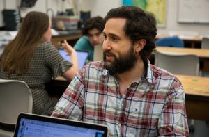 A student wearing a flannel shirt sits in a classroom.