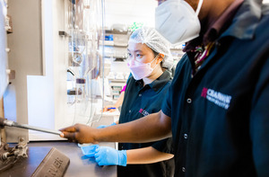 Food Science students work in a lab. They are wearing face masks while operating equipment.