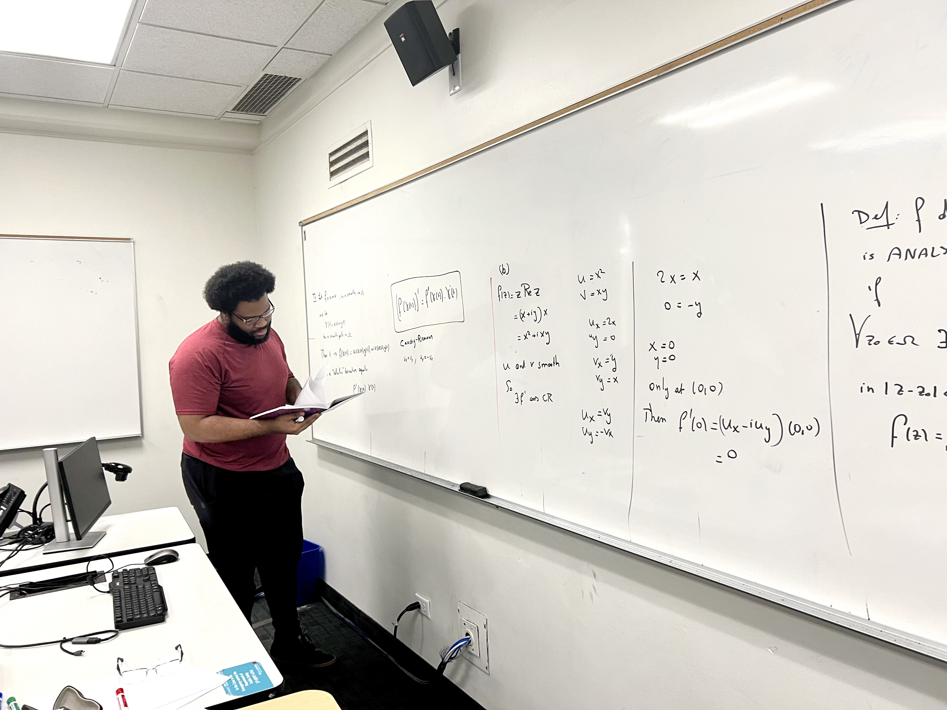 Student with textbook writing at whiteboard.