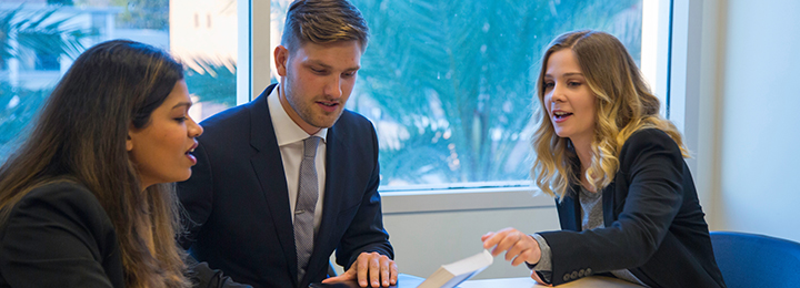 three business students sitting at a table studying