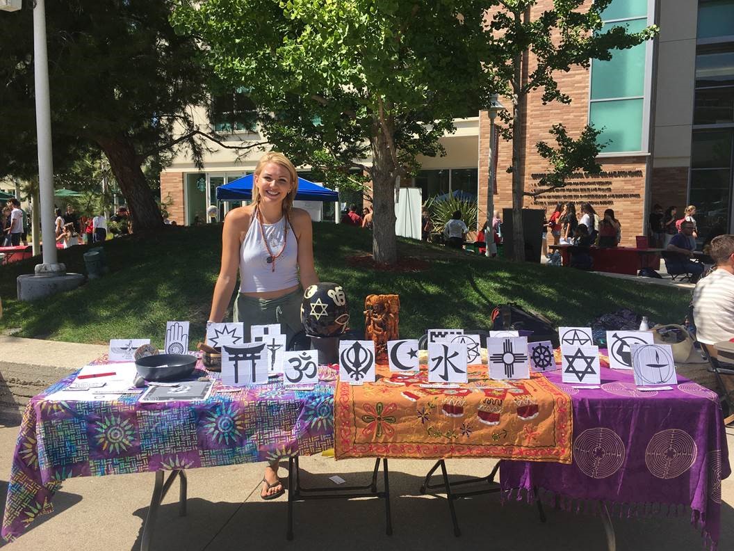 Department of Religious Studies student standing behind information booth table